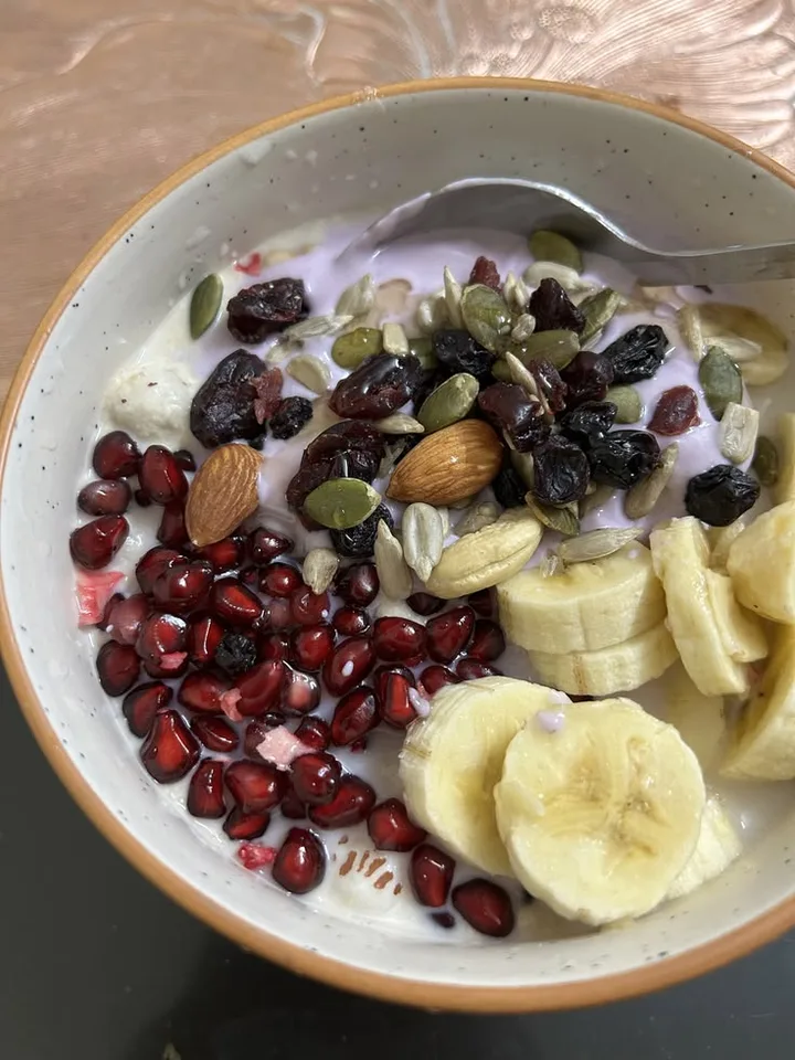 Yogurt breakfast bowl with banana, pomegranate, almonds and seeds